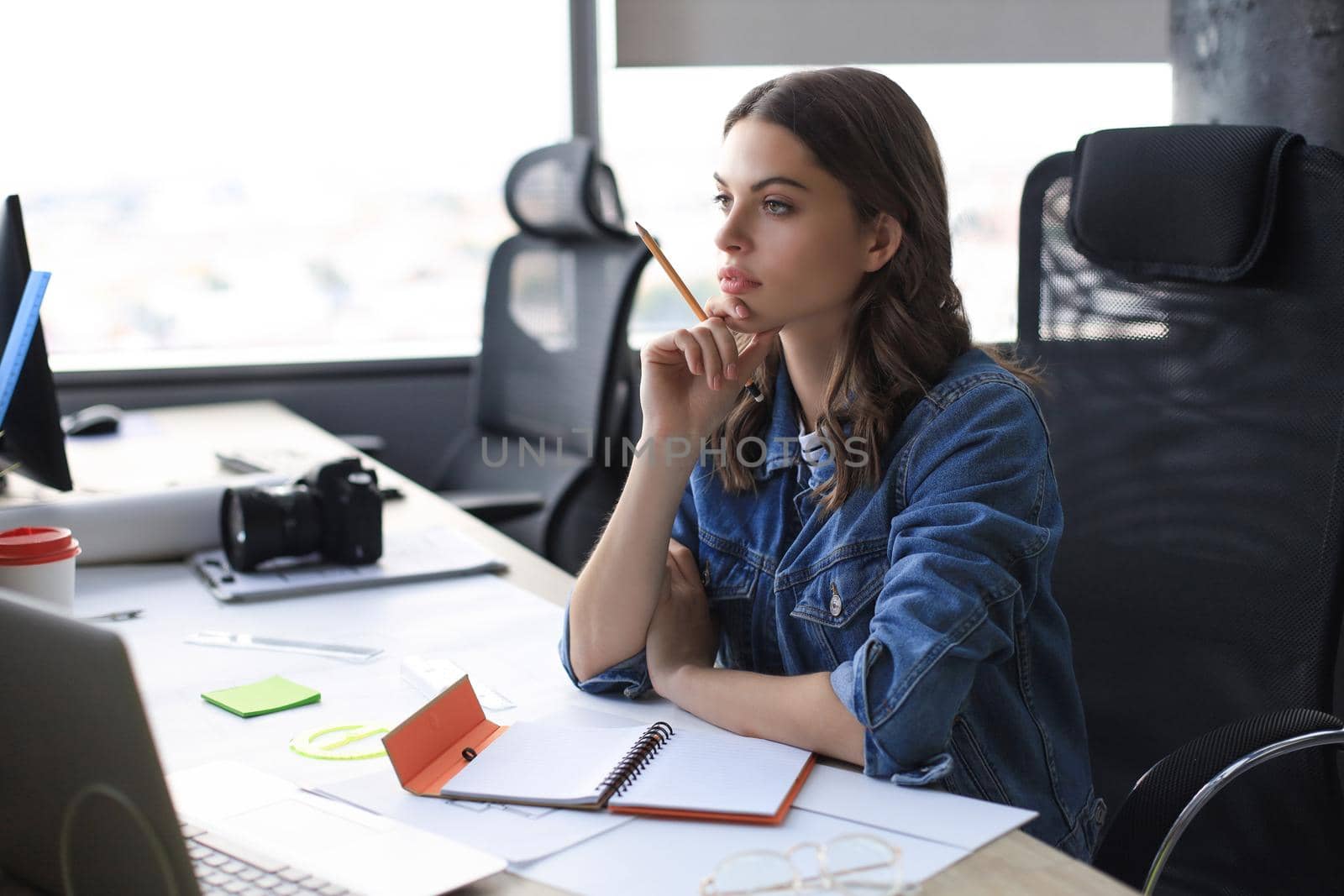 Concentrated young woman writing something down while working in the office. by tsyhun