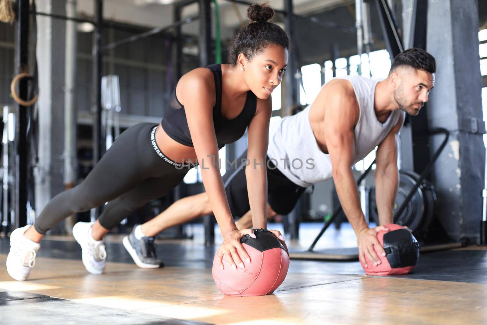 Beautiful young sports couple is working out with medicine ball in gym