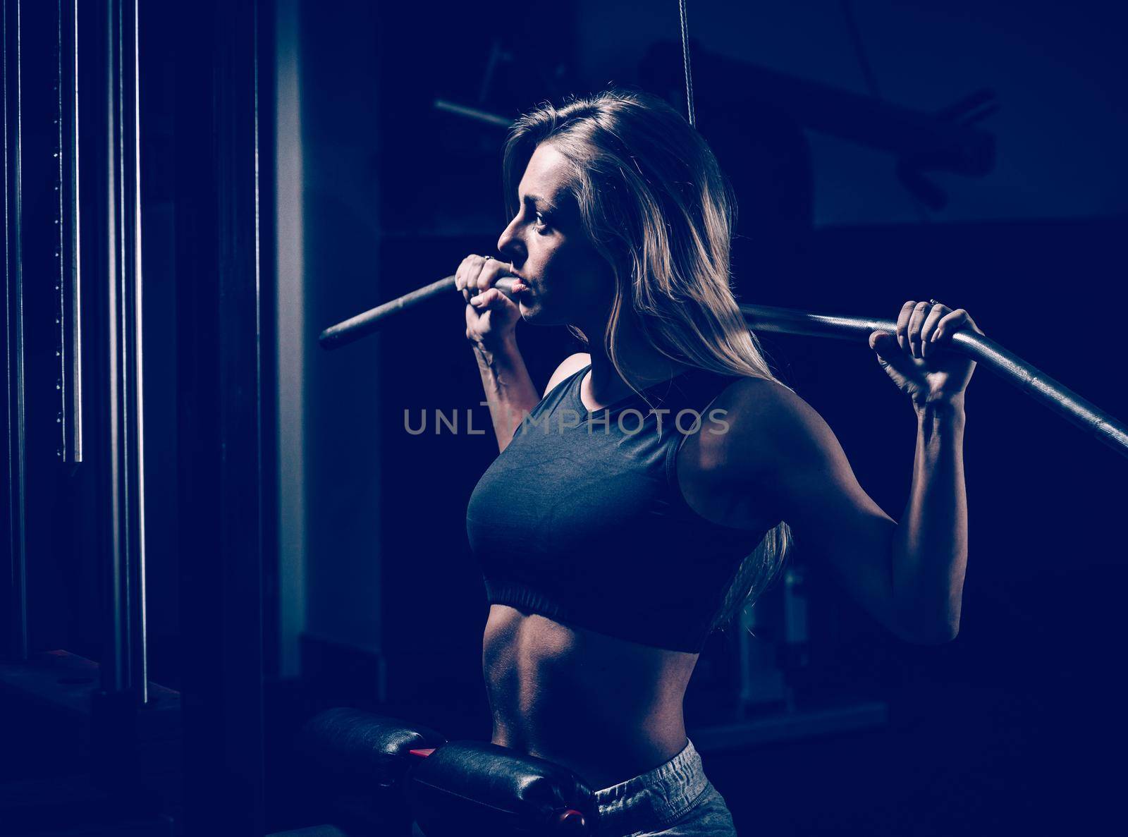 Young business woman doing exercise on a fitness machine in a fitness club. Photo on a dark background.