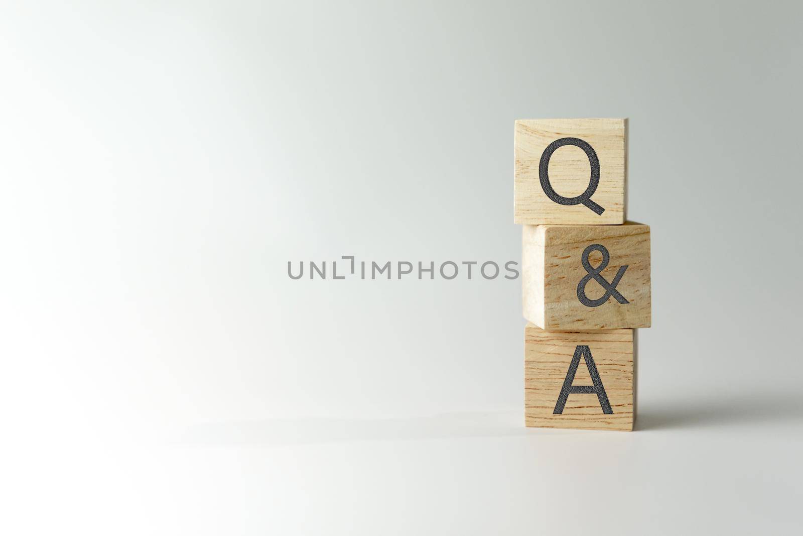 Q and A alphabet on wooden cube in hand hold with background. Question and answer meaning concept.