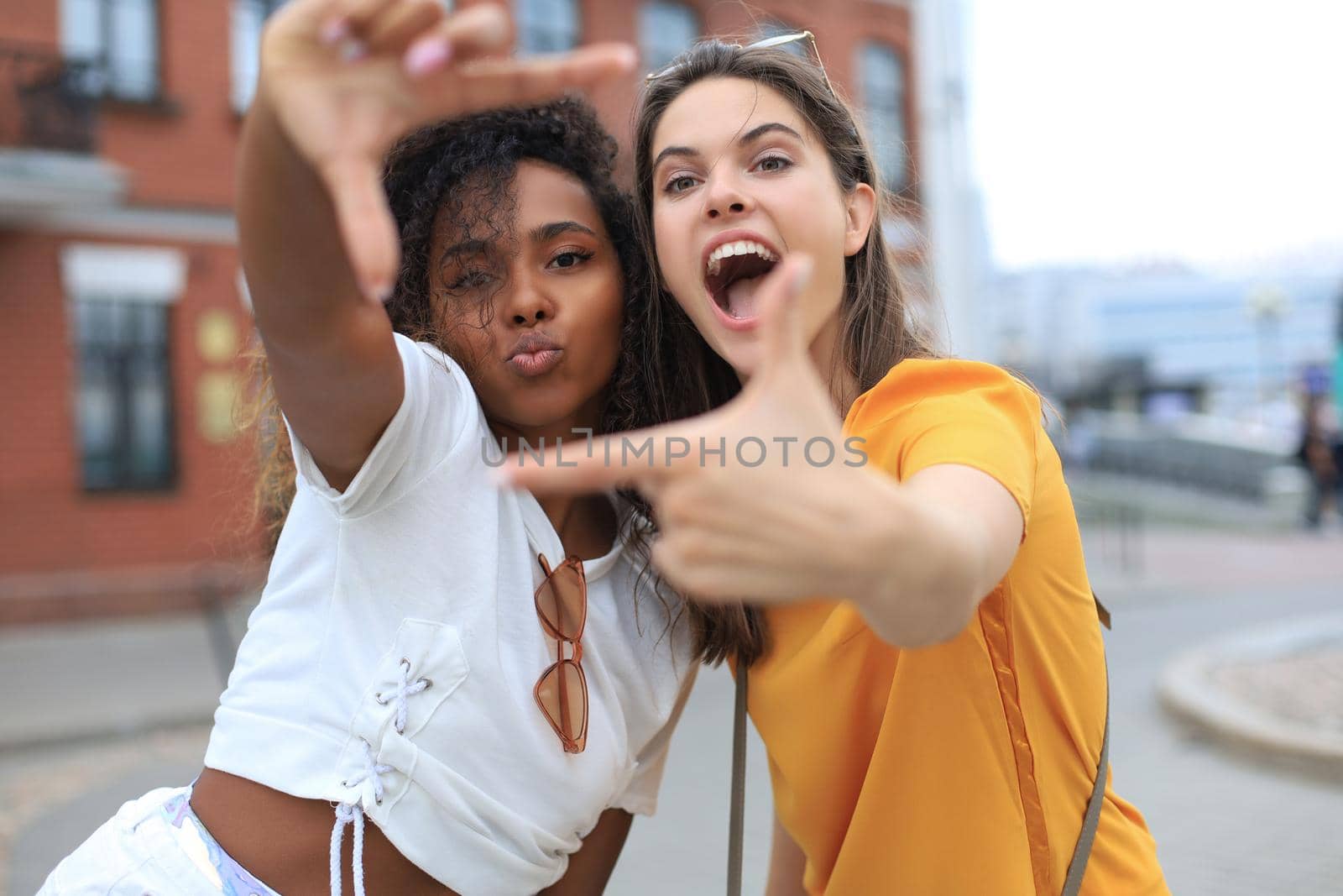 Cute young girls friends having fun together, taking a selfie at the city