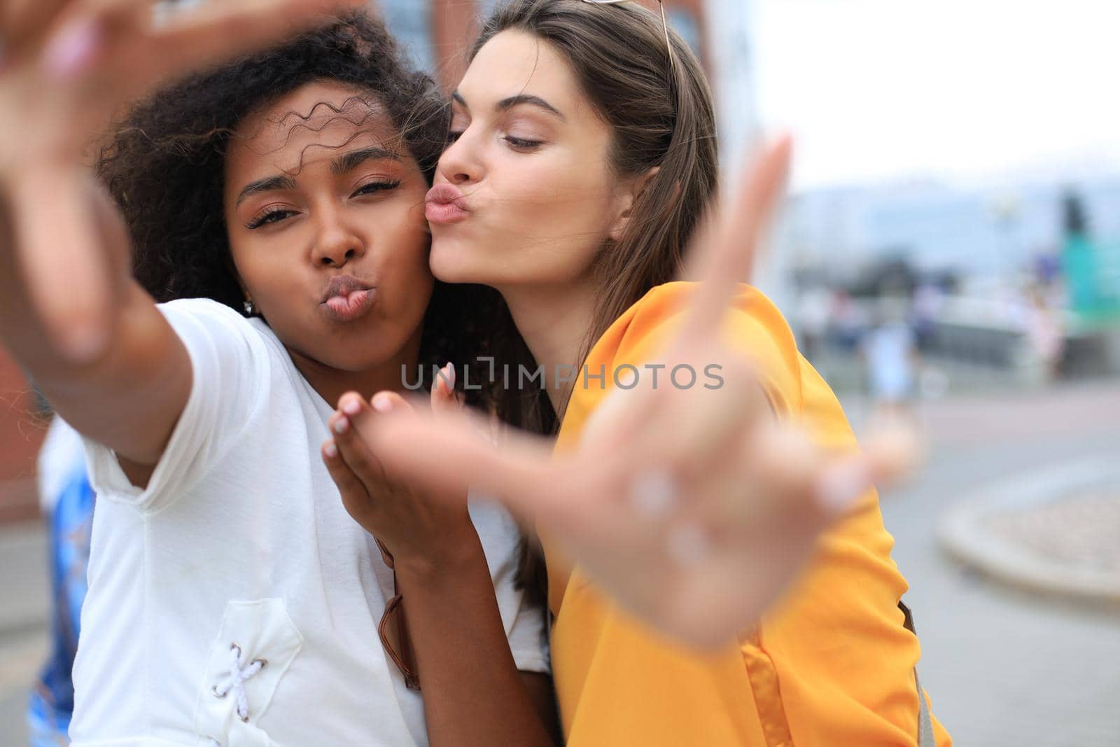 Cute young girls friends having fun together, taking a selfie at the city