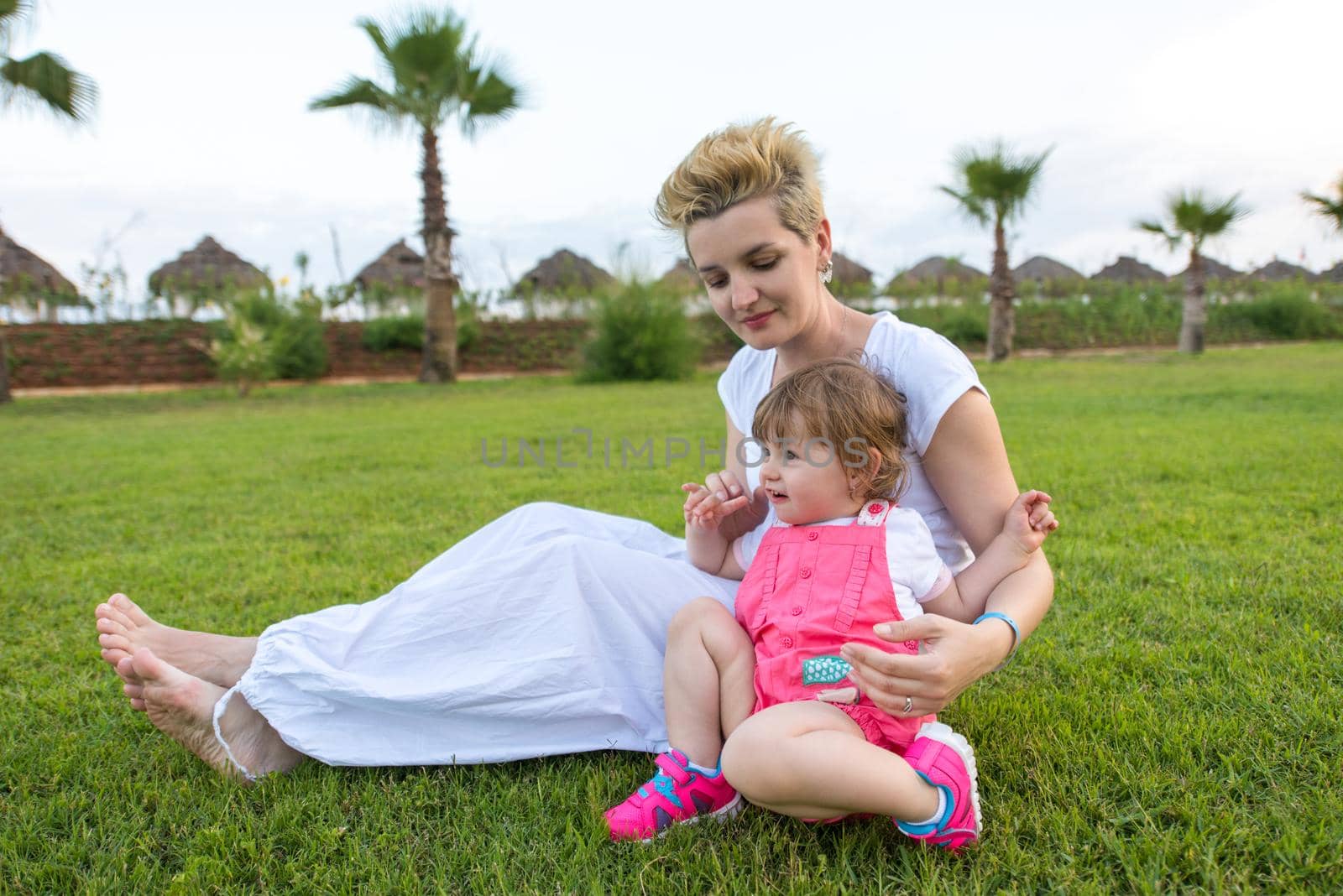 Young Mother and cute little daughter enjoying free time playing outside at backyard on the grass, happy family in nature concept