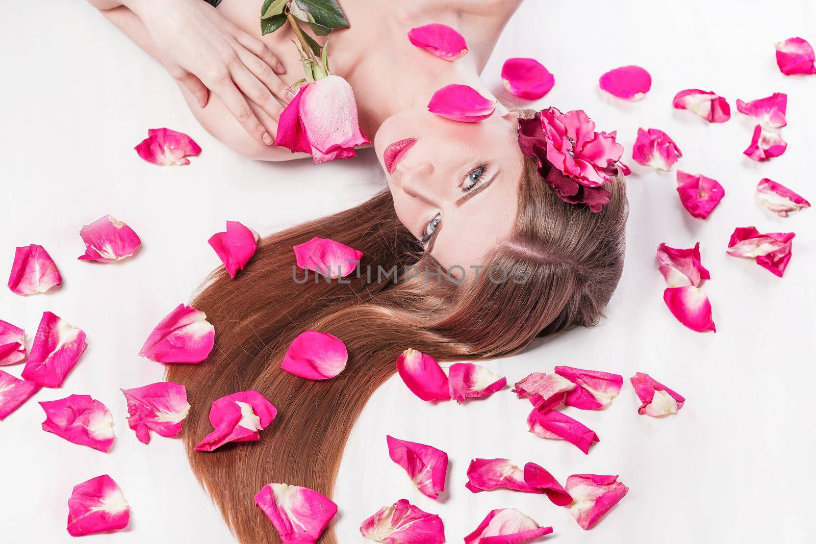 beautiful young woman on rose petals background. photo with copy space