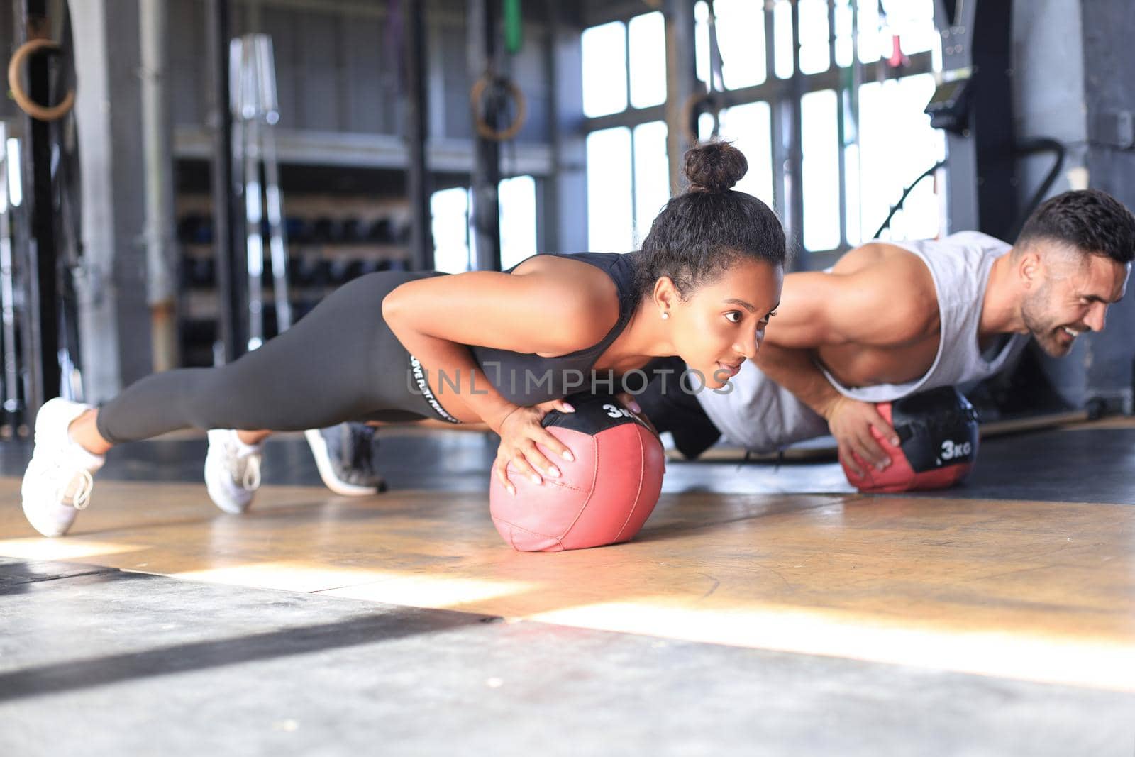 Beautiful young sports couple is working out with medicine ball in gym