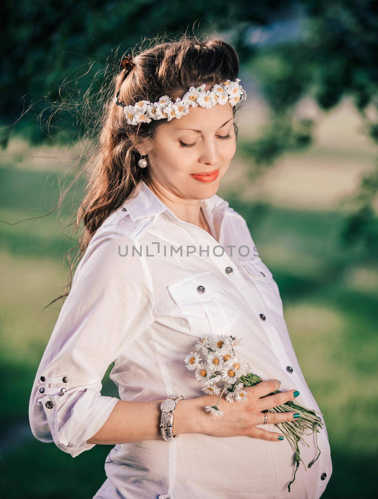 portrait of a cute pregnant woman with a bouquet of daisies . the concept of motherhood