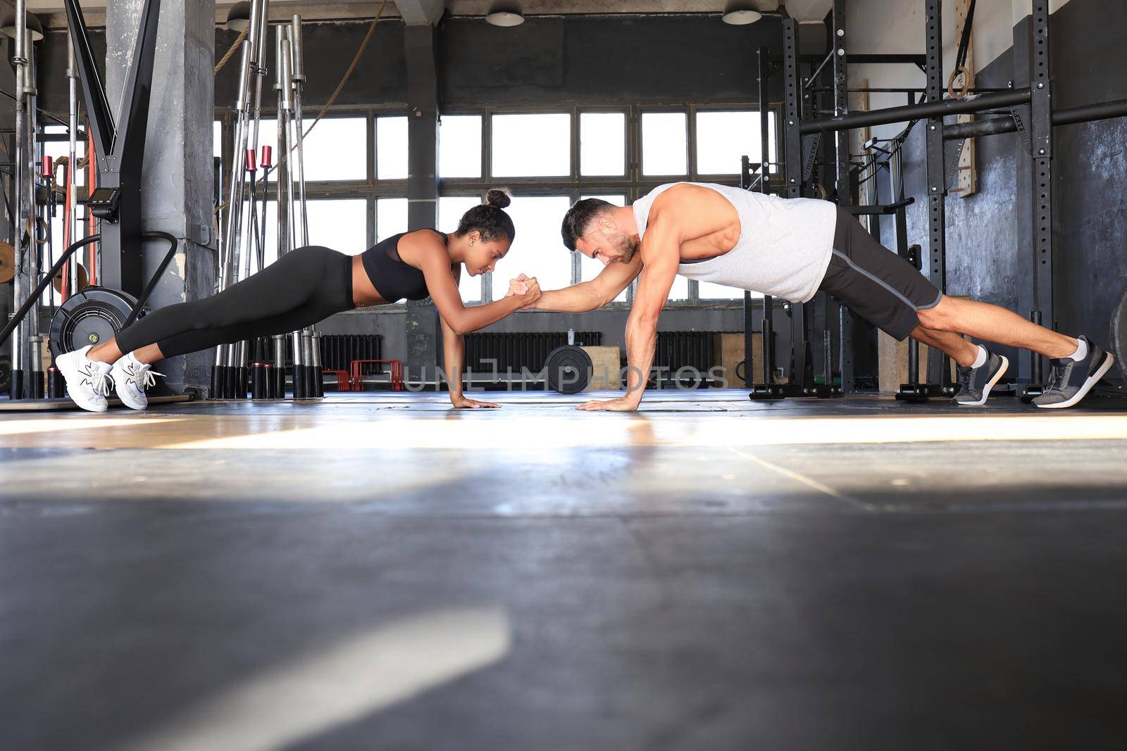 Sporty couple doing plank exercise in gym
