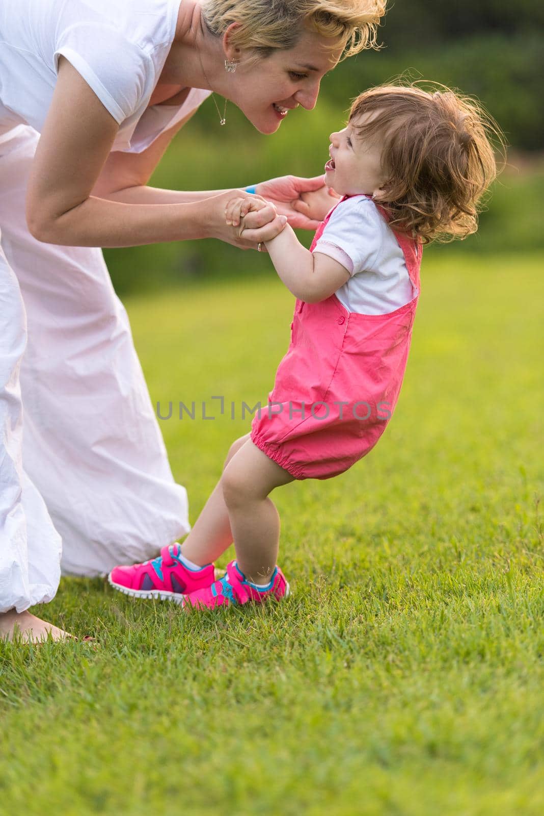 Young Mother and cute little daughter enjoying free time playing outside at backyard on the grass, happy family in nature concept