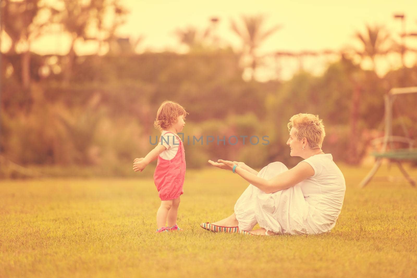 Young Mother and cute little daughter enjoying free time playing outside at backyard on the grass, happy family in nature concept