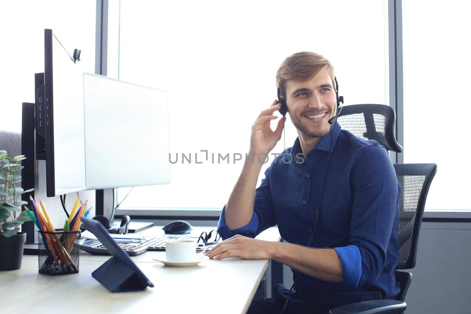 Happy young male customer support executive working in office. by tsyhun