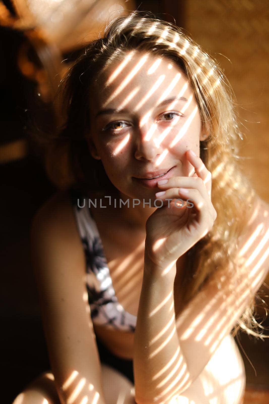 Portrait of young european woman wearing bra, striped shadows. Concept of beautiful female person and home photosession.