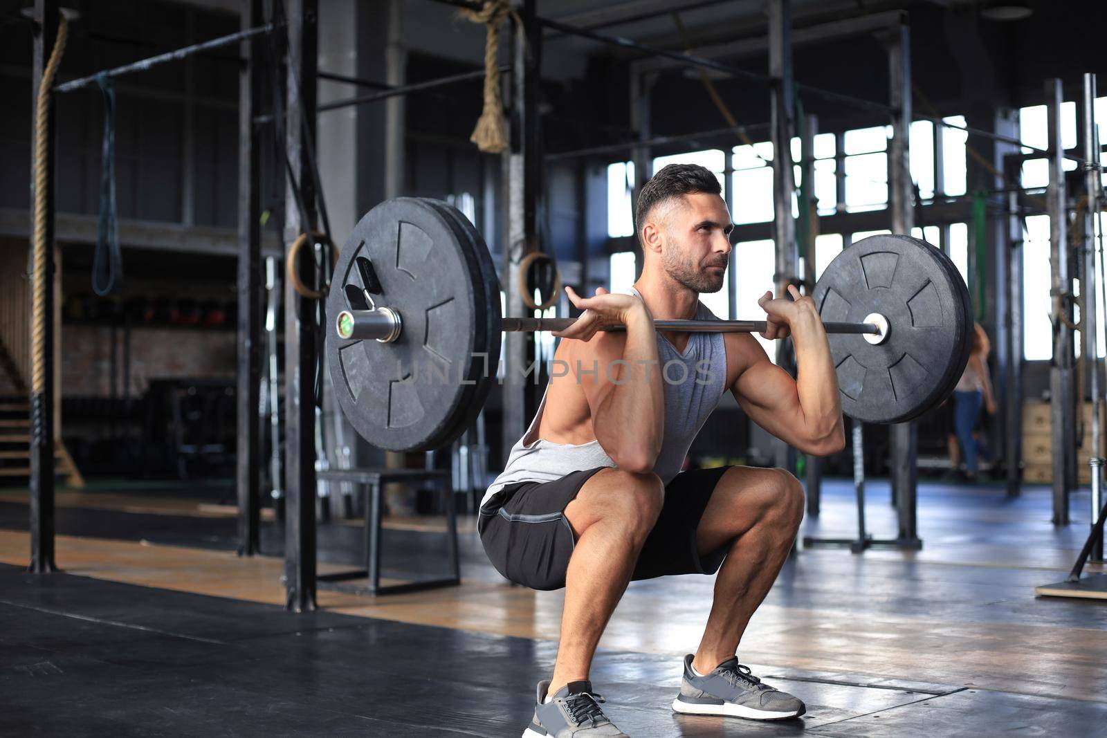 Muscular man working out in gym doing exercises with barbell at biceps