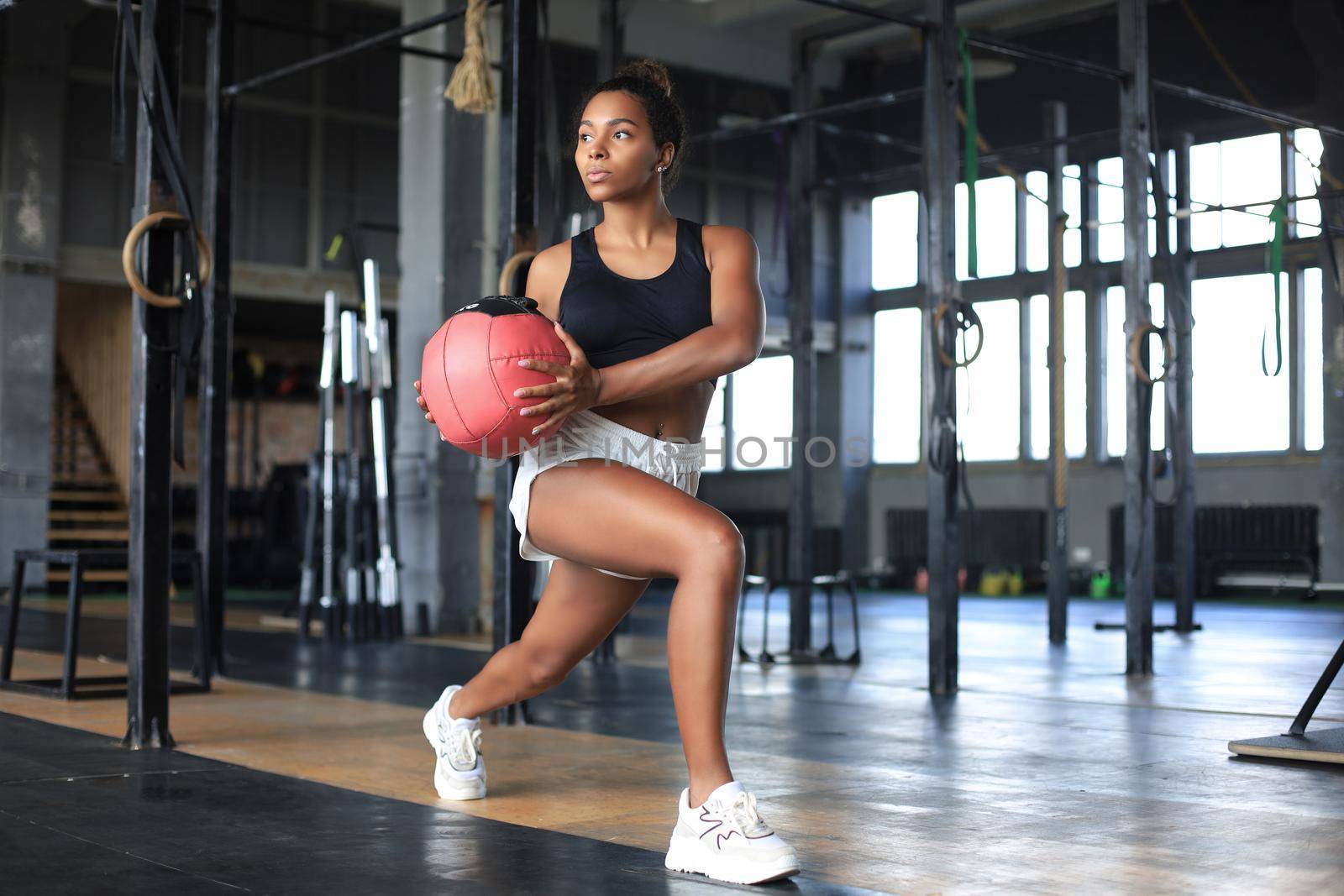 Fit and muscular woman exercising with medicine ball at gym