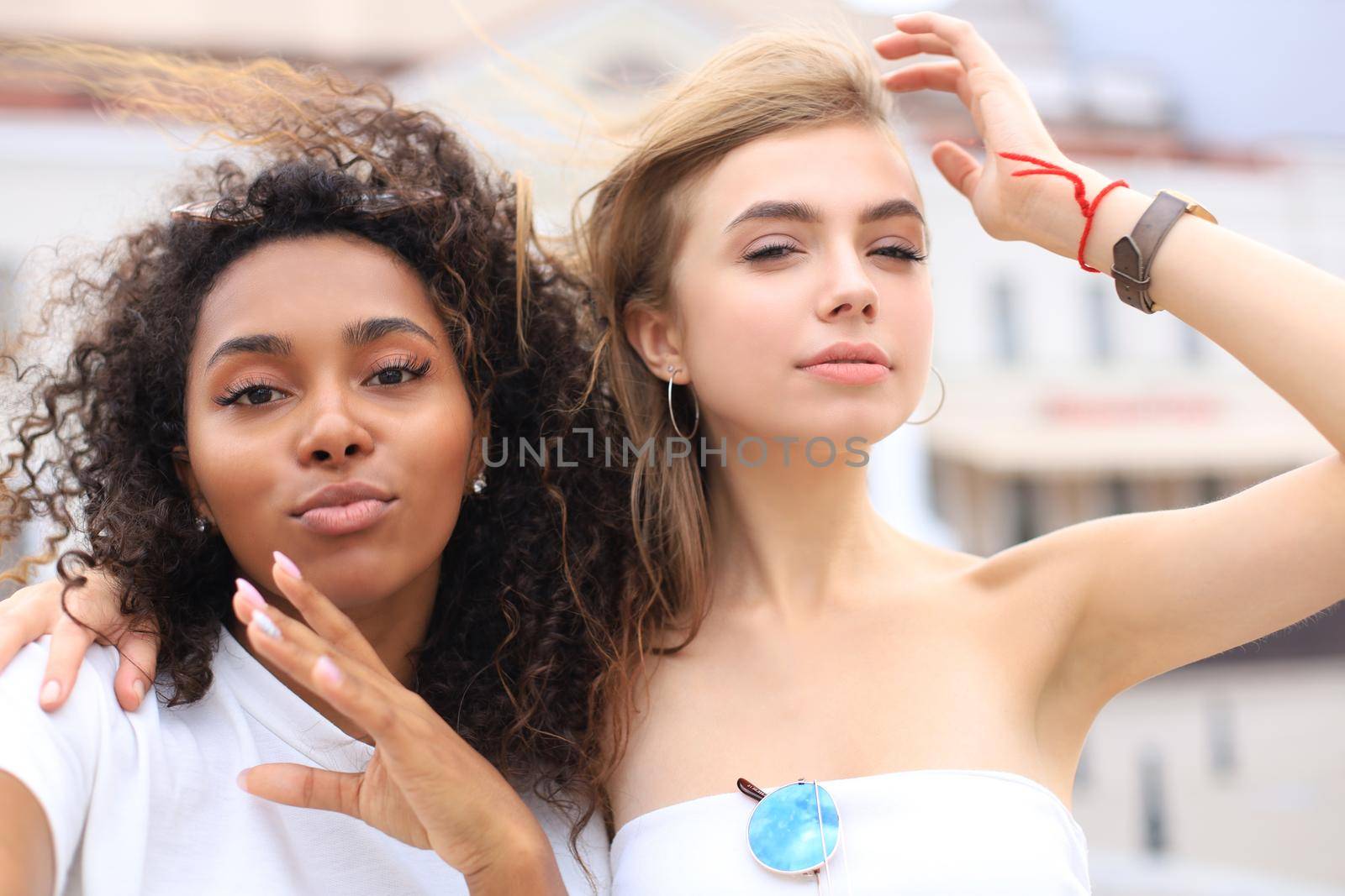 Young smiling hipster women in summer clothes posing on street.Female showing positive face emotions