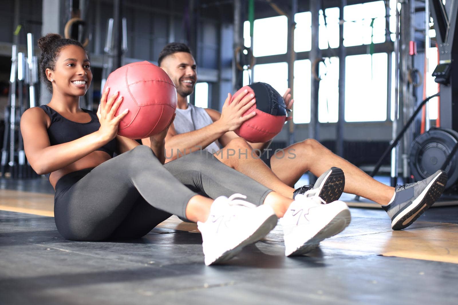 Beautiful young sports couple is working out with medicine ball in gym