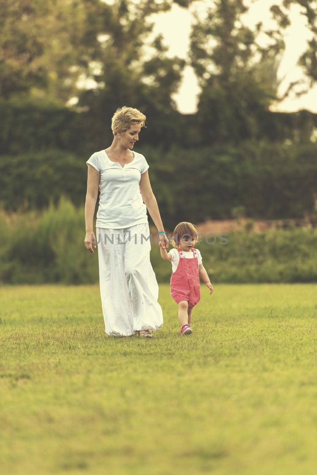 Young Mother and cute little daughter enjoying free time playing outside at backyard on the grass, happy family in nature concept