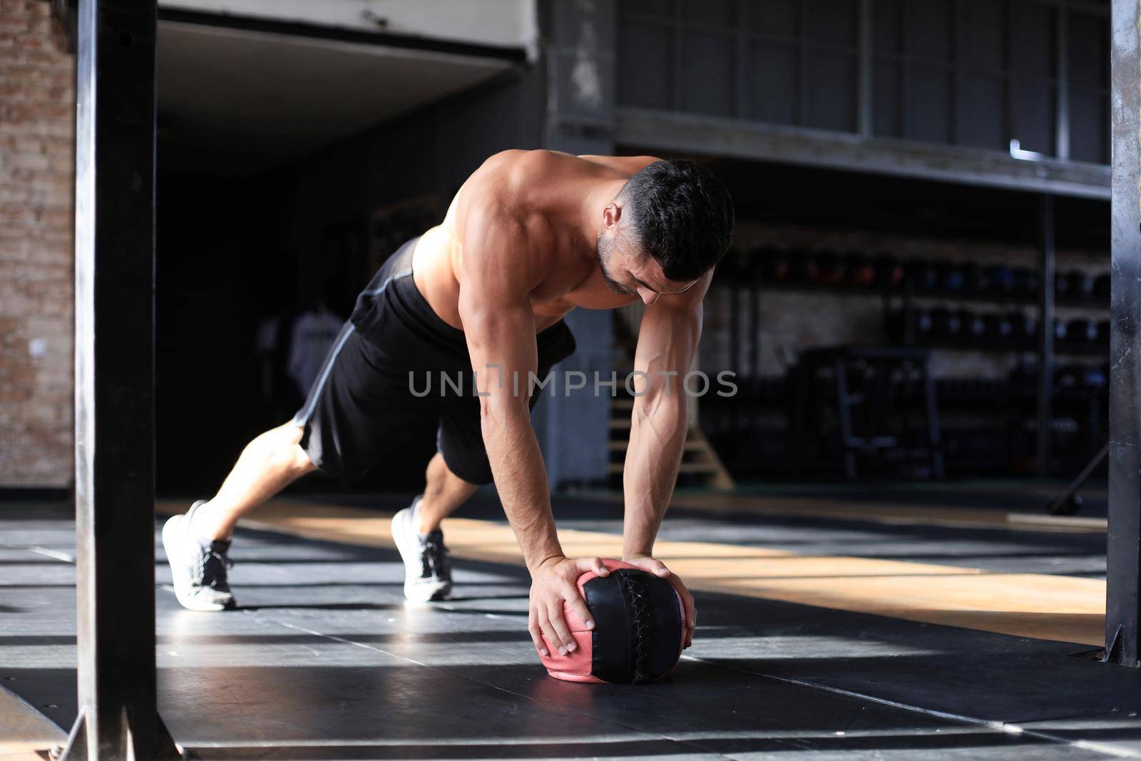 Fit and muscular man exercising with medicine ball at gym