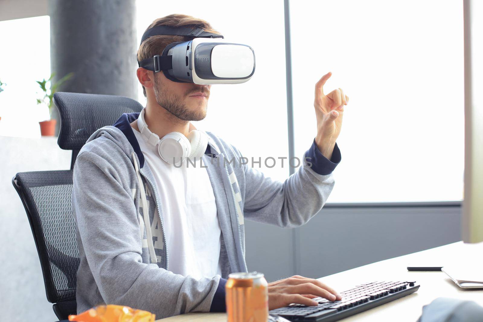 Young bearded man wearing virtual reality glasses in modern interior design coworking studio. by tsyhun