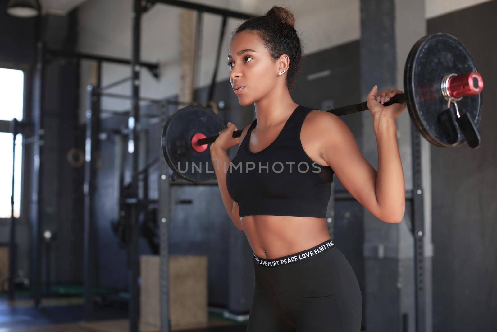 Beautiful woman exercising squatting with barbell at gym