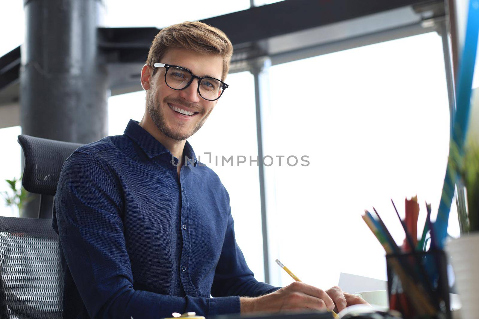 Good looking young business man drawing something while working in the office