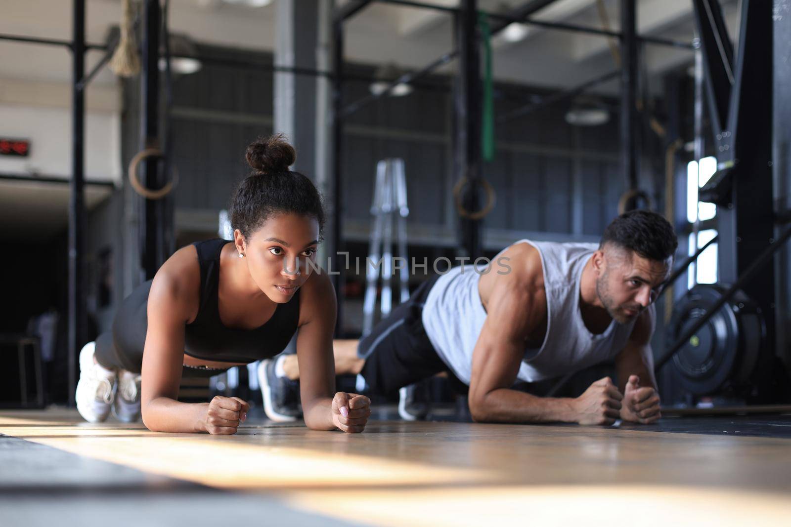 Portrait of beautiful young sports couple on a plank position
