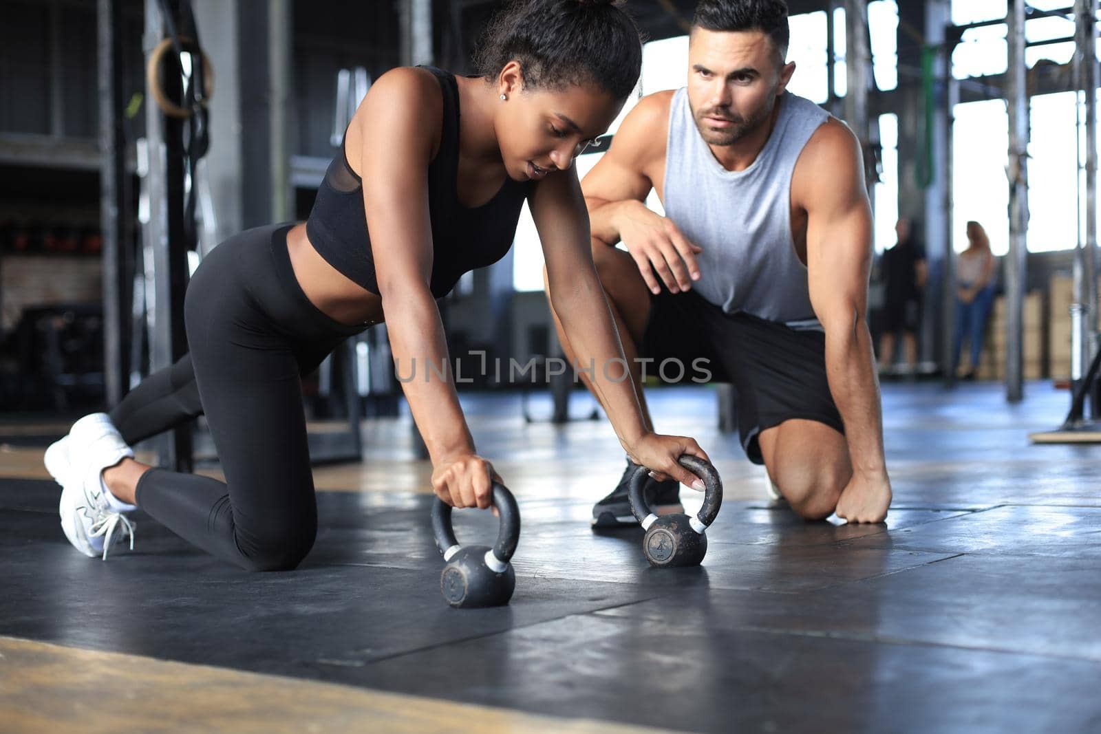 Sporty woman doing push-up in a gym, her boyfriend is watching her