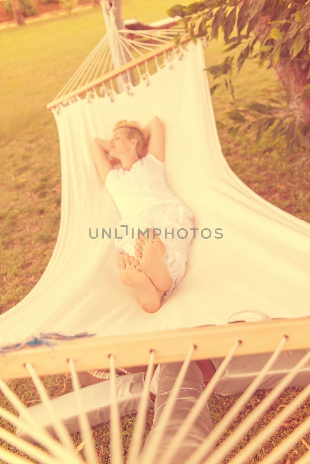 beautiful young woman enjoying free time while resting on white hammock in the backyard