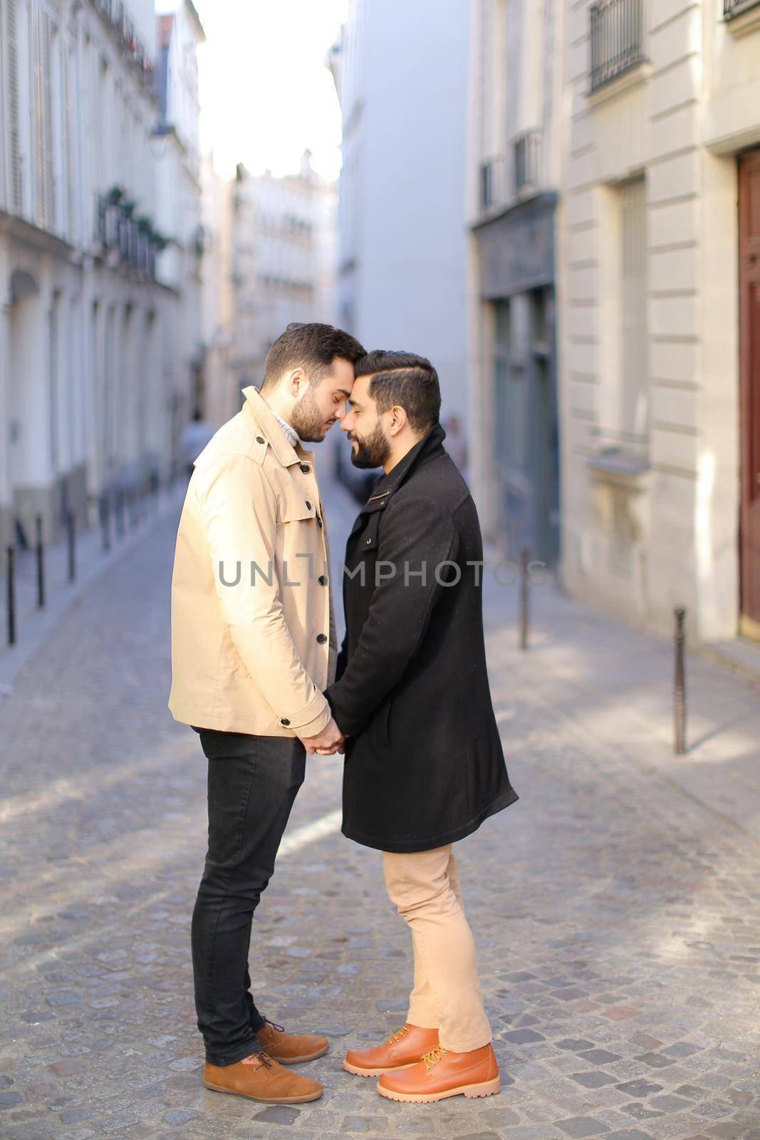 Two hugging happy gays in city, buildings i background. by sisterspro