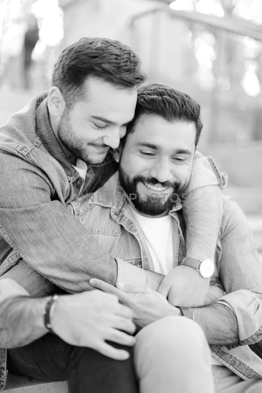 Black and white photo of caucasian young gays hugging and wearing jeans shirts. Concept of same sex couple and relationship.