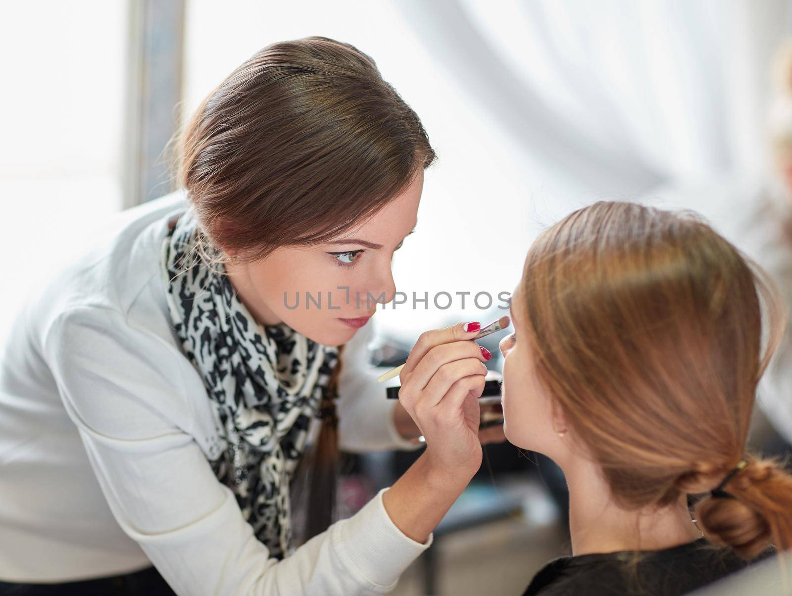professional makeup artist does make-up in a beauty salon by SmartPhotoLab