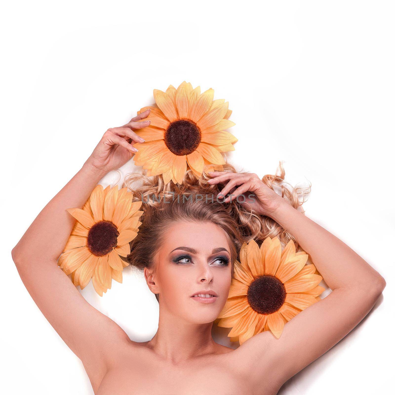 beautiful woman model lying among the flowers of a sunflower. skin care and healthy lifestyle concept