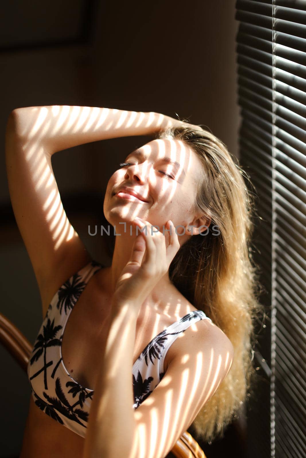 Portrait of young woman wearing bra, striped shadows. Concept of beautiful female person and home photosession.