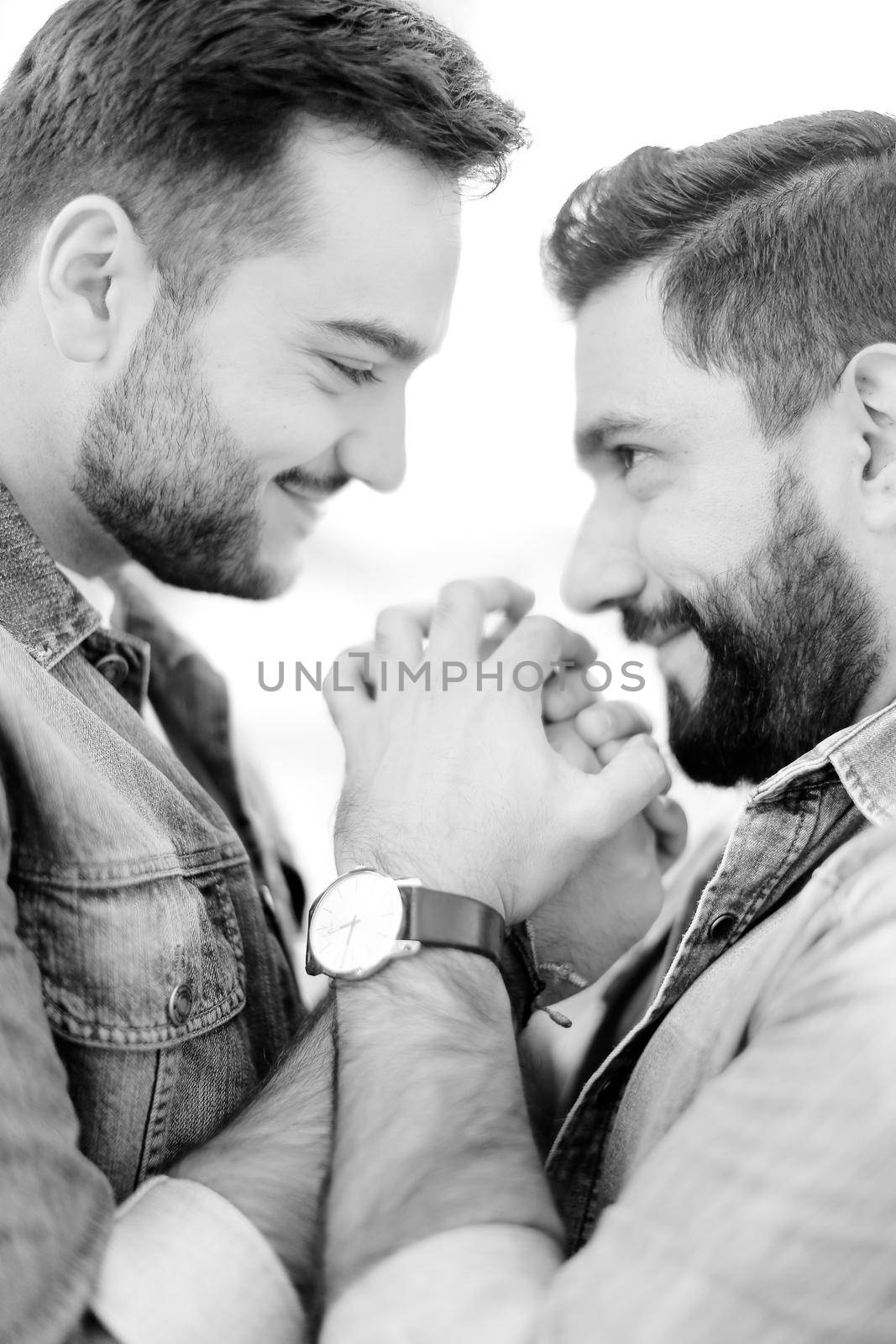 Black and white portrait of young handsome gays holding hands and wearing jeans shirts. Concept of realtionship and same sex couple, lgbt.