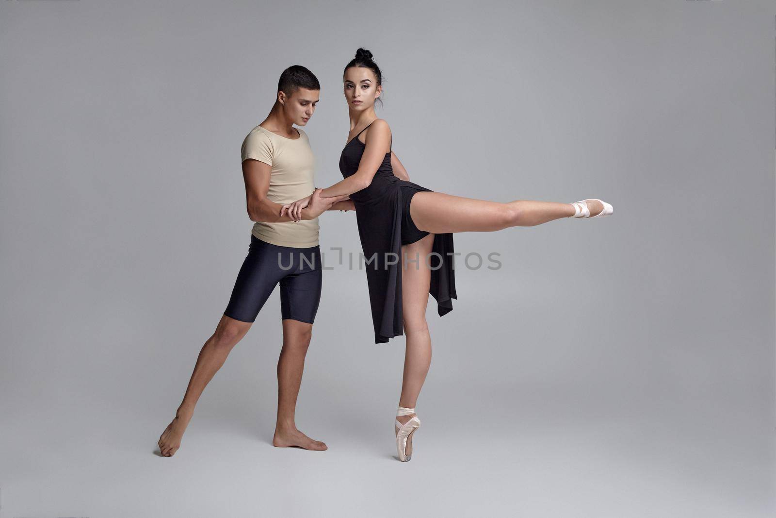 Two athletic modern ballet dancers are posing against a gray studio background. by nazarovsergey