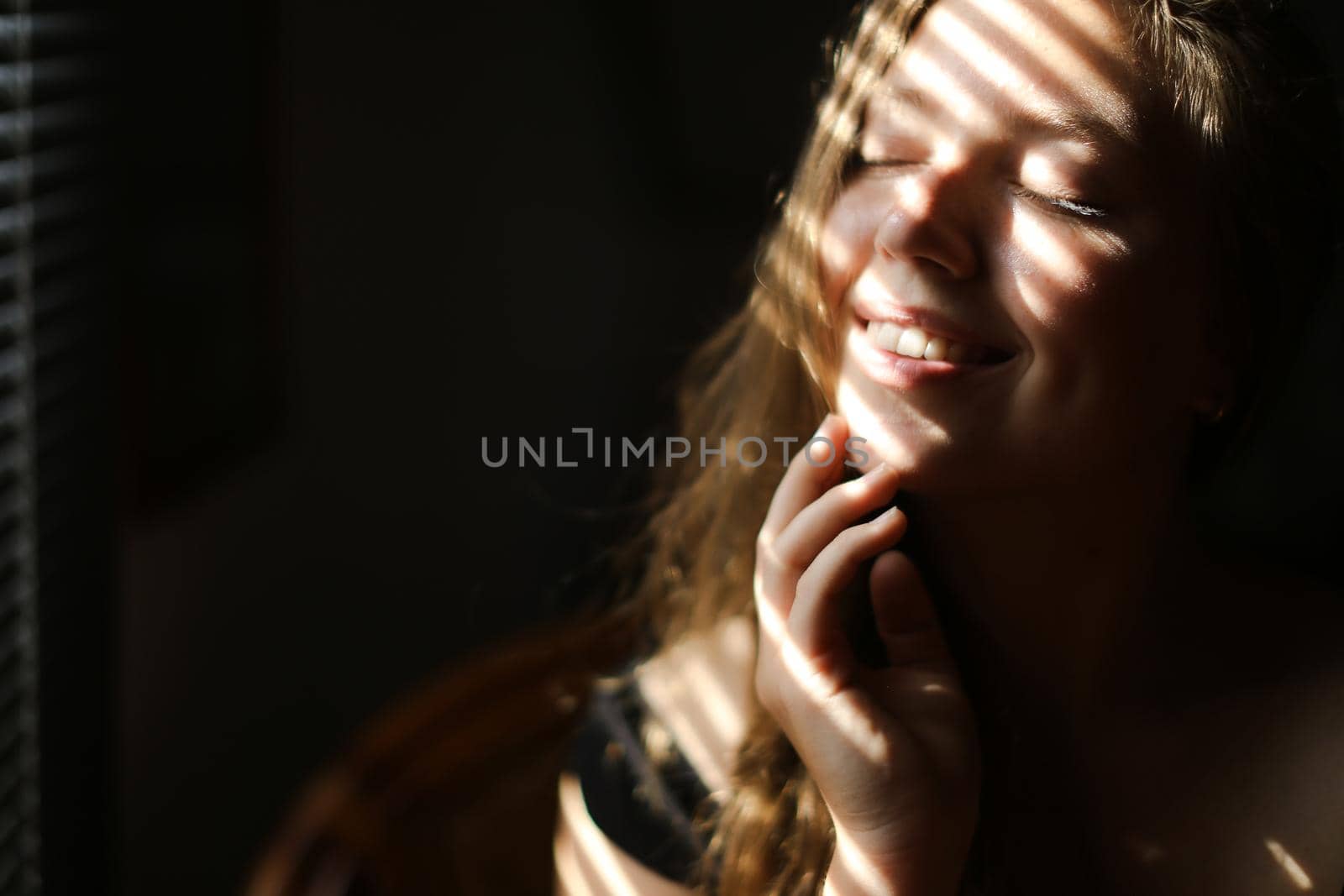 Close up portrait of young happy girl with closed eyes and striped shadows. Concept of private photo session and beautiful femaleperson with eveday makeup.