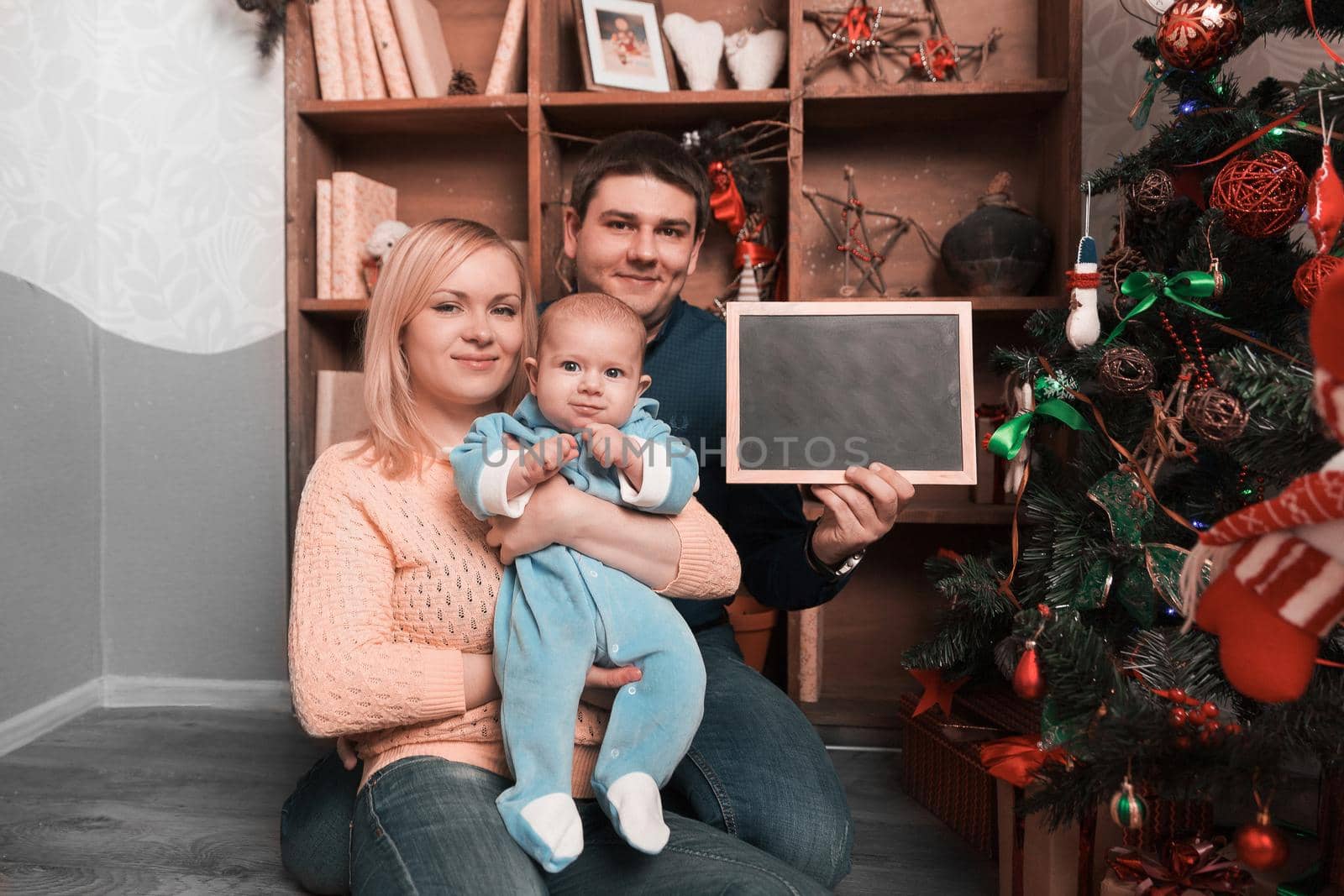 young happy parents showing blank Christmas card . holiday concept