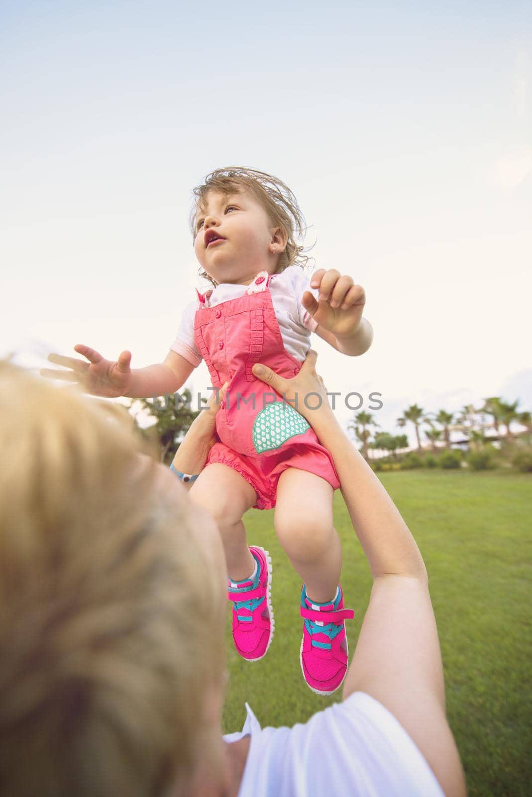 Young Mother and cute little daughter enjoying free time playing outside at backyard on the grass, happy family in nature concept