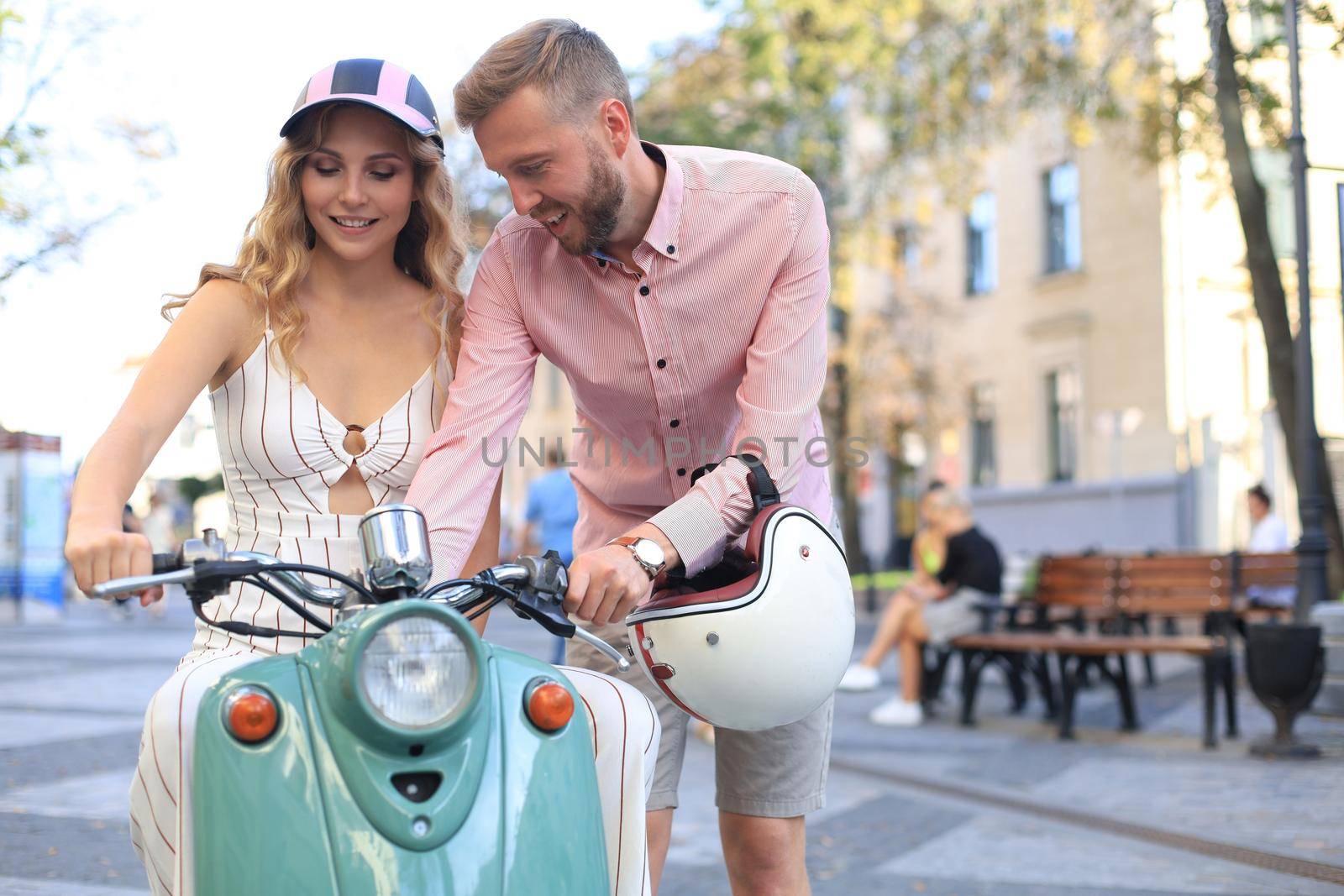 Happy young couple riding scooter in town. Handsome guy and young woman travel. Adventure and vacations concept