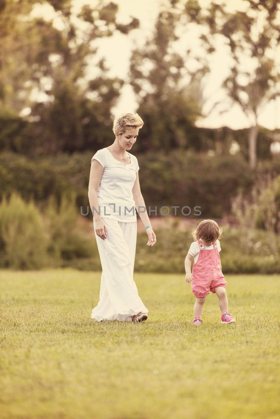 Young Mother and cute little daughter enjoying free time playing outside at backyard on the grass, happy family in nature concept