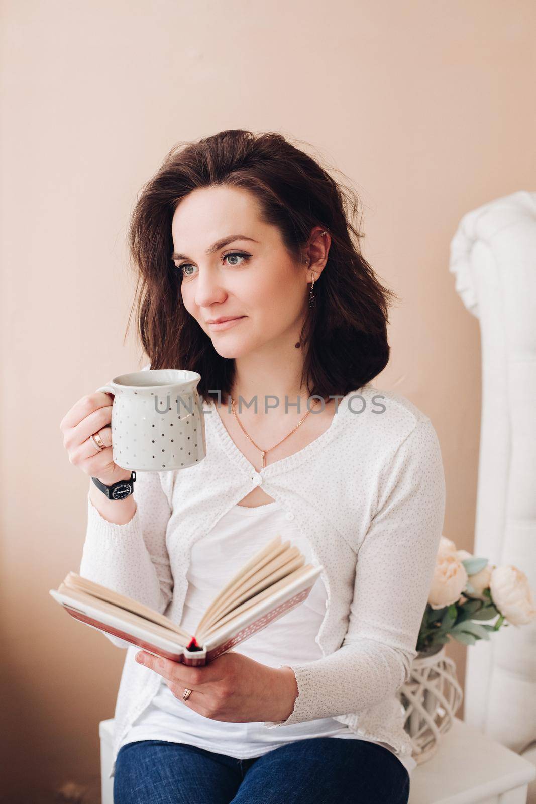 Lovely woman with coffee and book. Caucasian young woman with a book drinking coffee looking away pensively. by StudioLucky