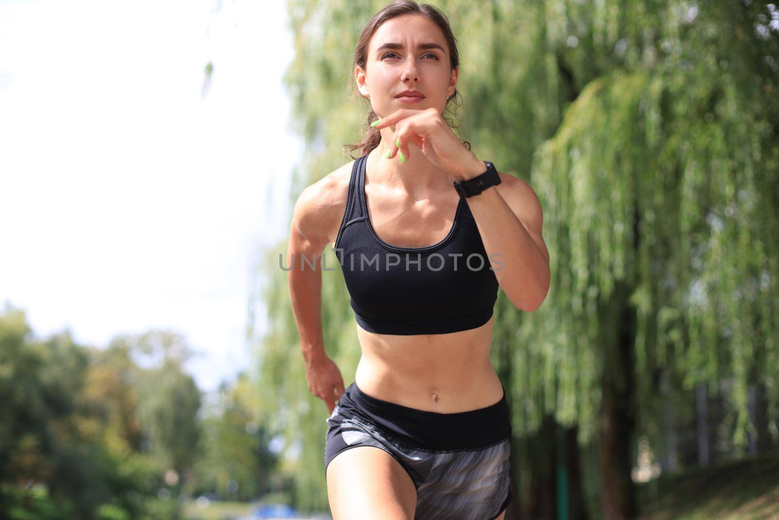 Young woman in sports clothing running while exercising outdoors