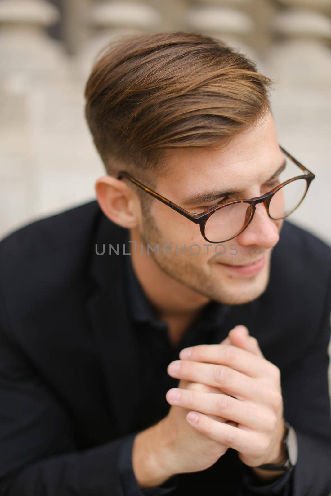 Closeup portrait of european man wearing black suit and glasses. Concept of male beauty and fashionable model.