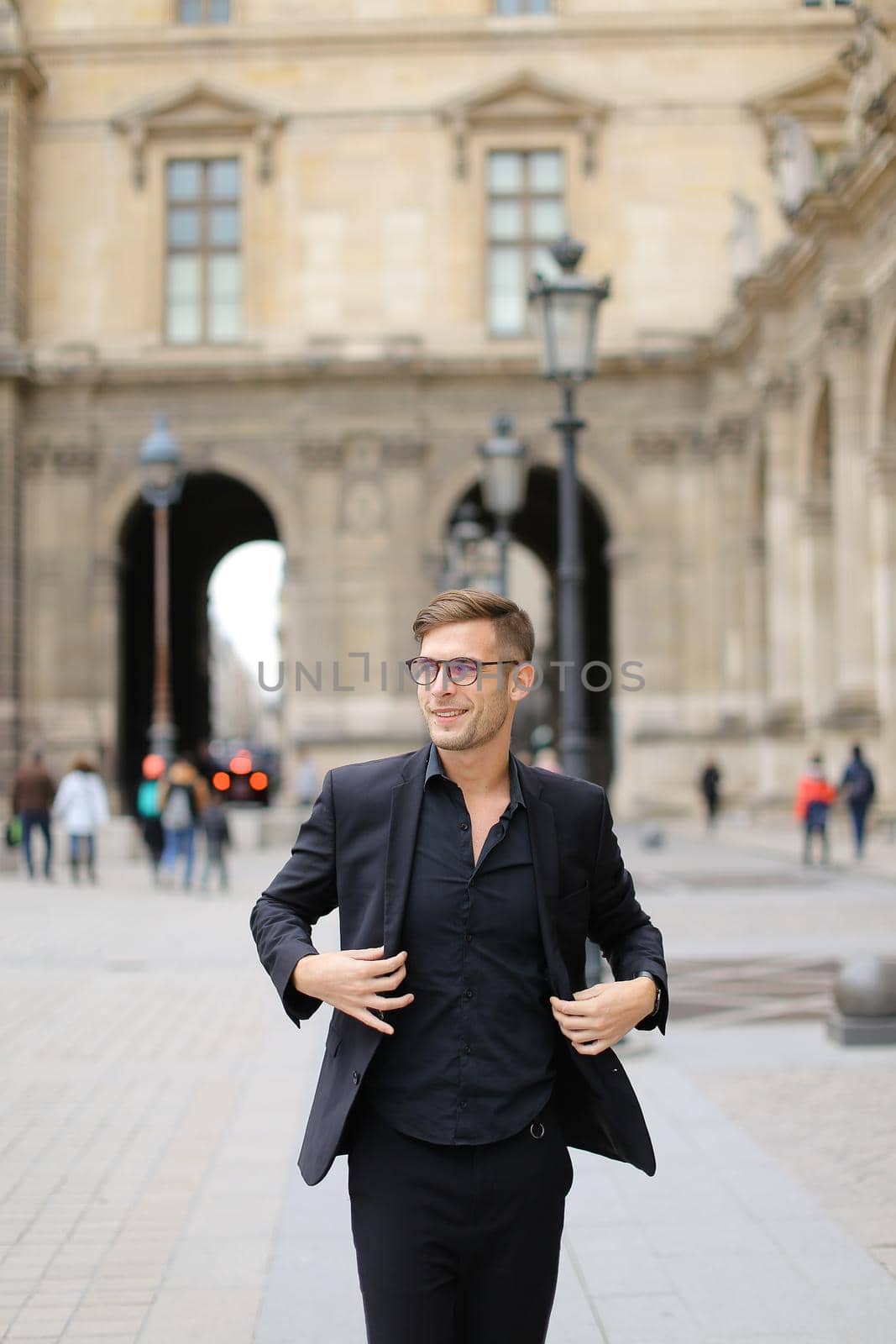 Young man walking in Paris and wearing black suit. by sisterspro