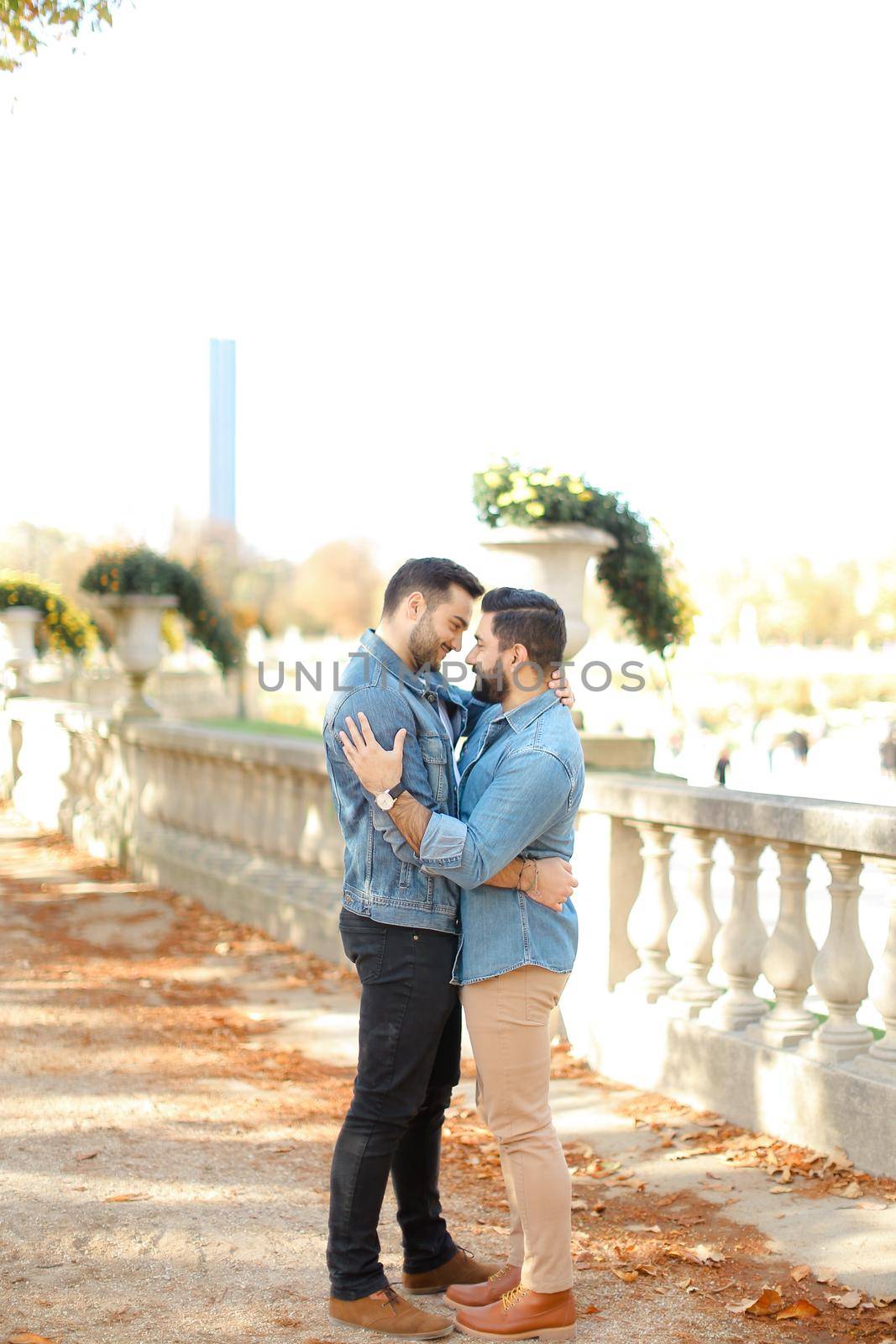 Caucasian young gays walking in autumn park and hugging on concrete stairs. Concept of same sex couple and relationship.