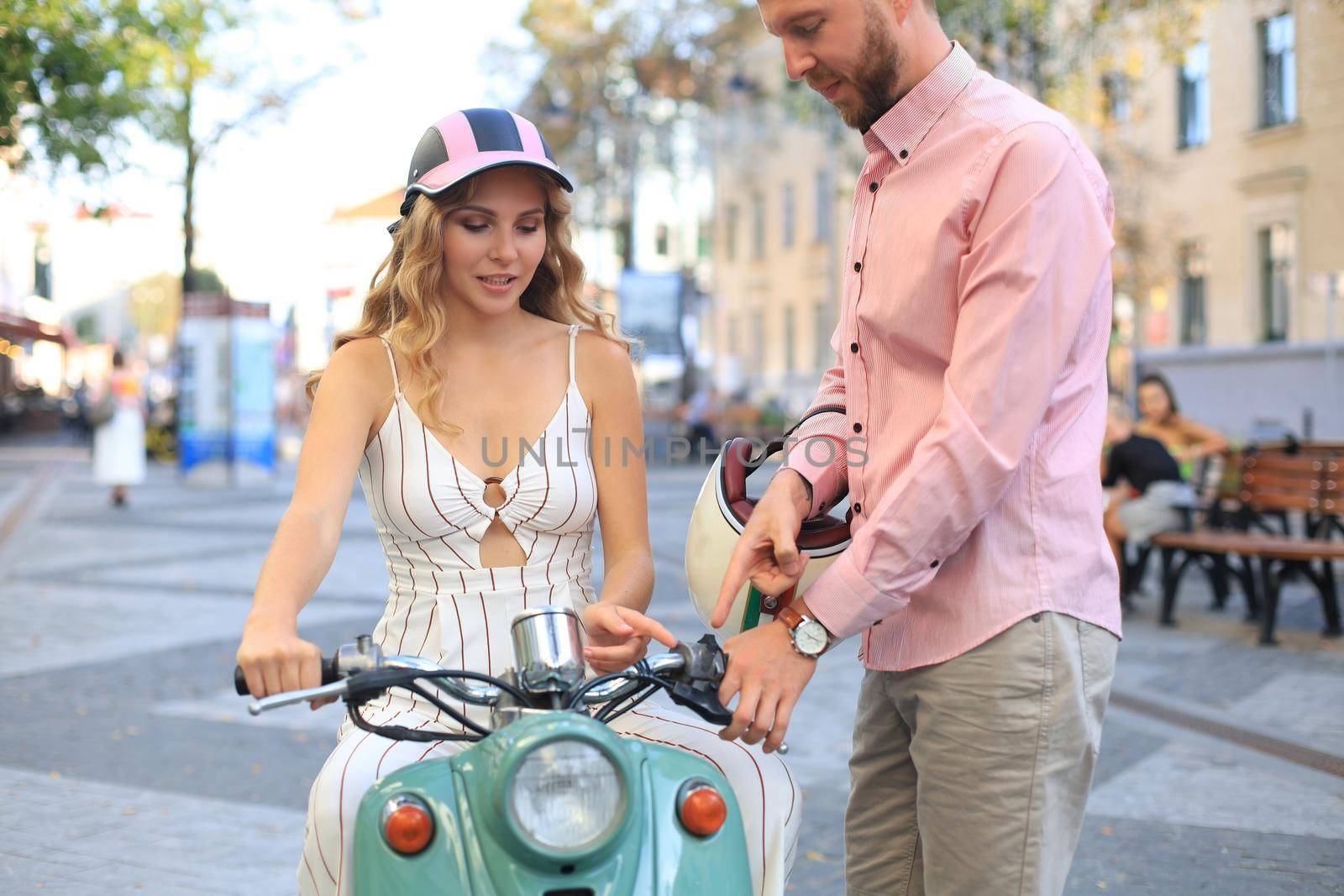 Happy young couple riding scooter in town. Handsome guy and young woman travel. Adventure and vacations concept