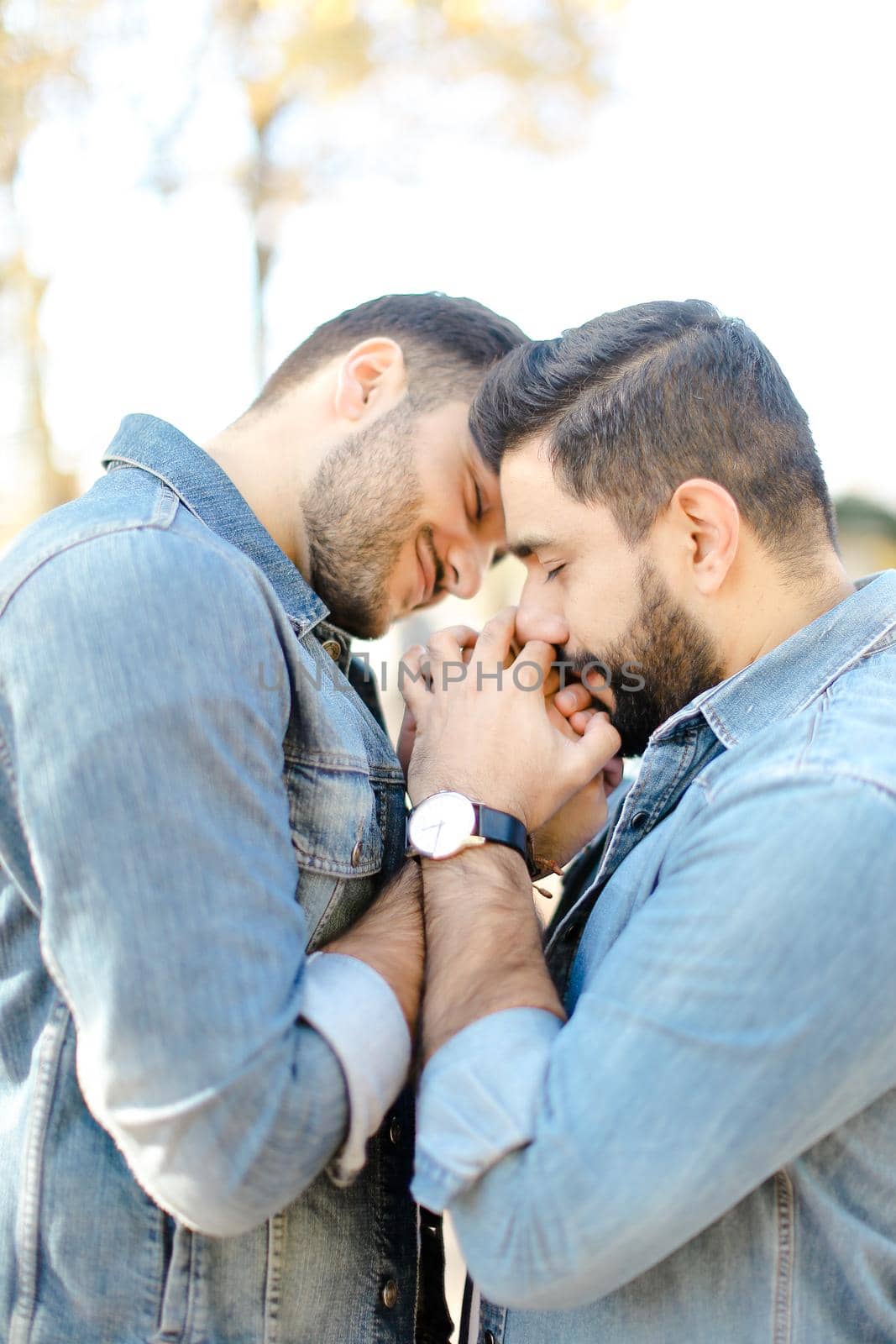 Portrait of young happy handsome gays holding hands and wearing jeans shirts. Concept of realtionship and same sex couple, lgbt.