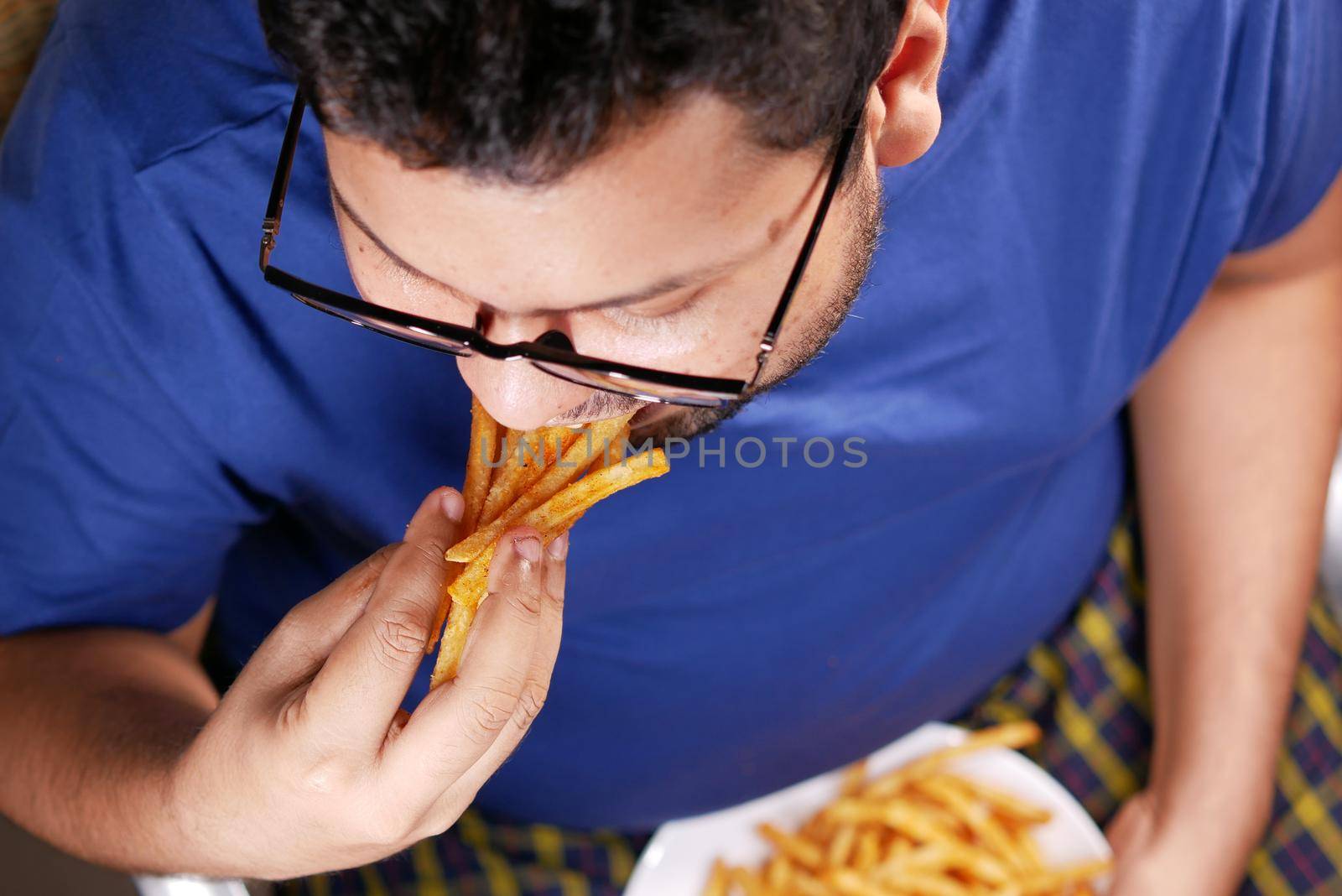 a fat man eating french fries while sited .