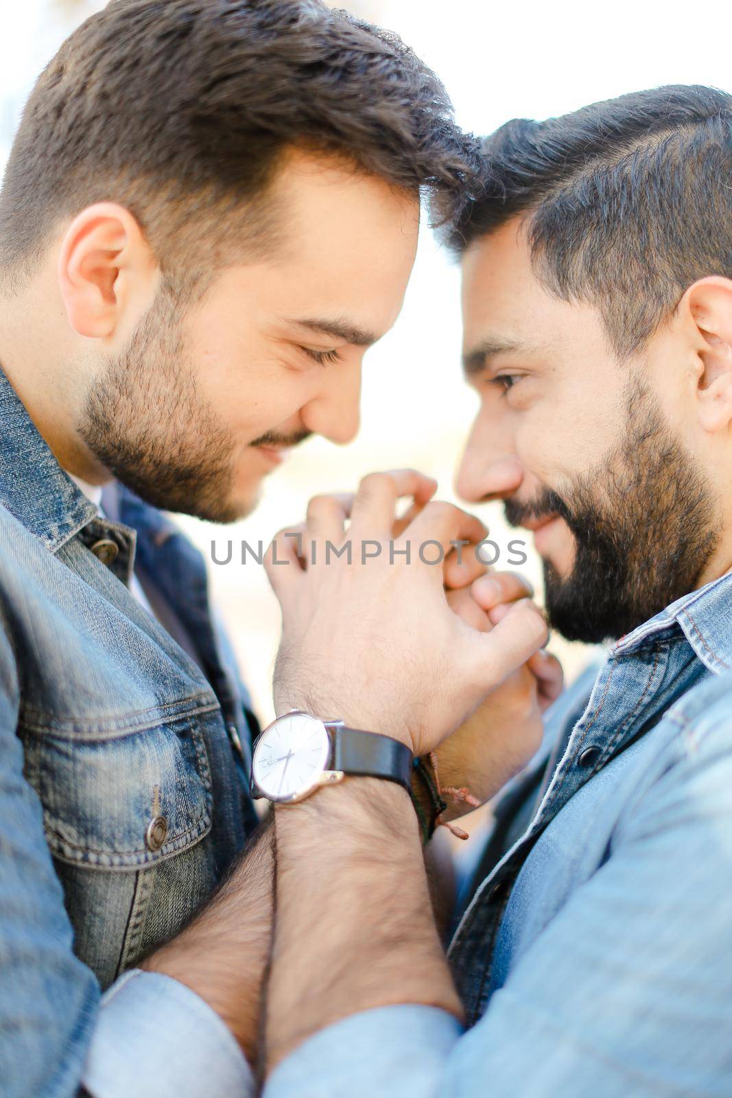 Portrait of young handsome gays holding hands and wearing jeans shirts. Concept of realtionship and same sex couple, lgbt.