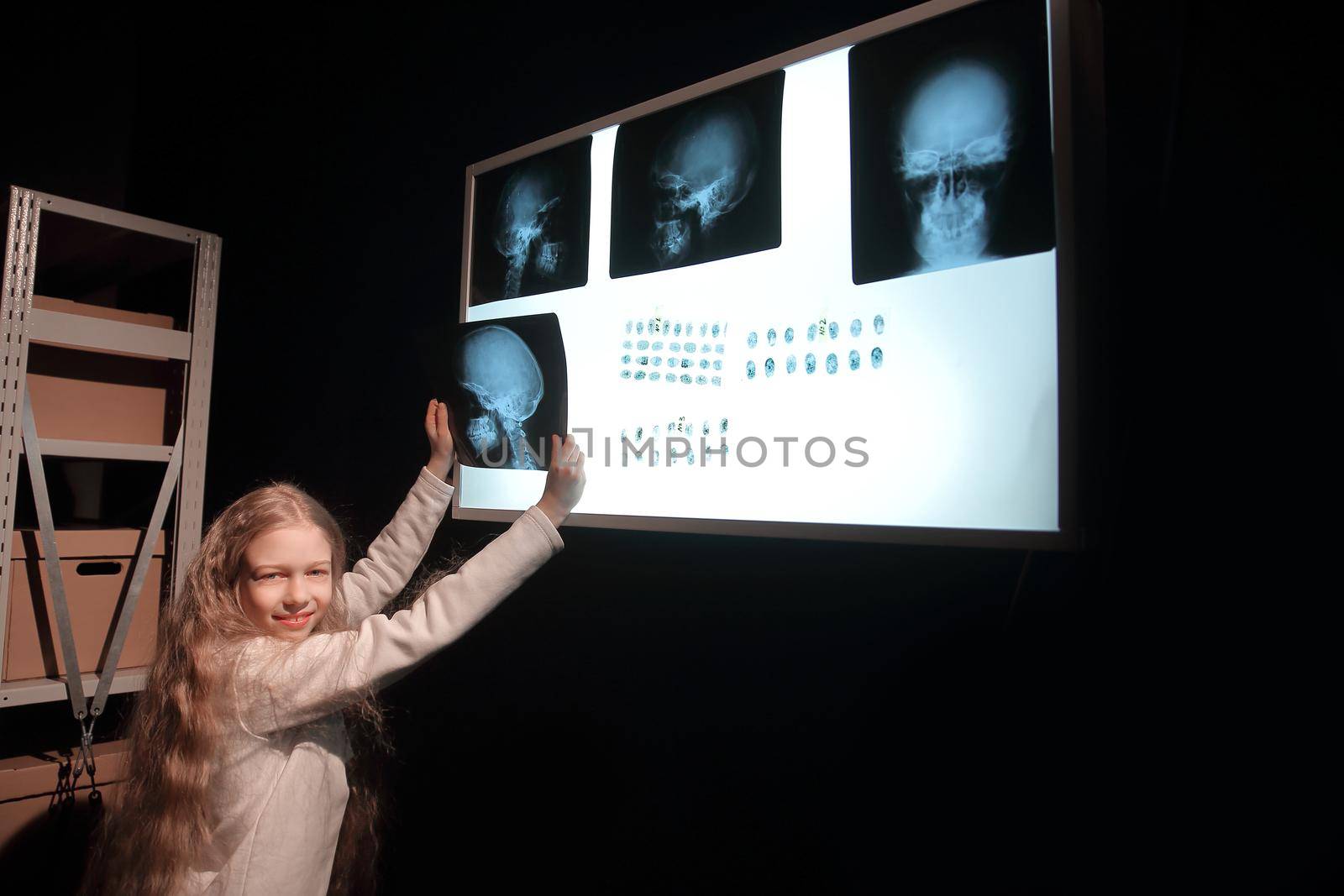 smiling detective girl looking at pictures and fingerprints . the concept of children's hobby