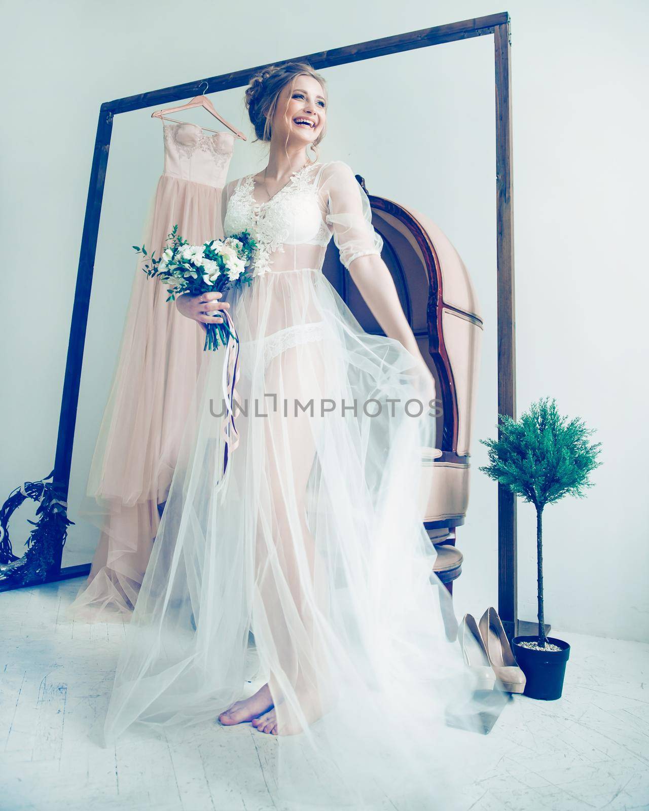 happy bride in boudoir dress standing in spacious hotel room. Morning of the bride.